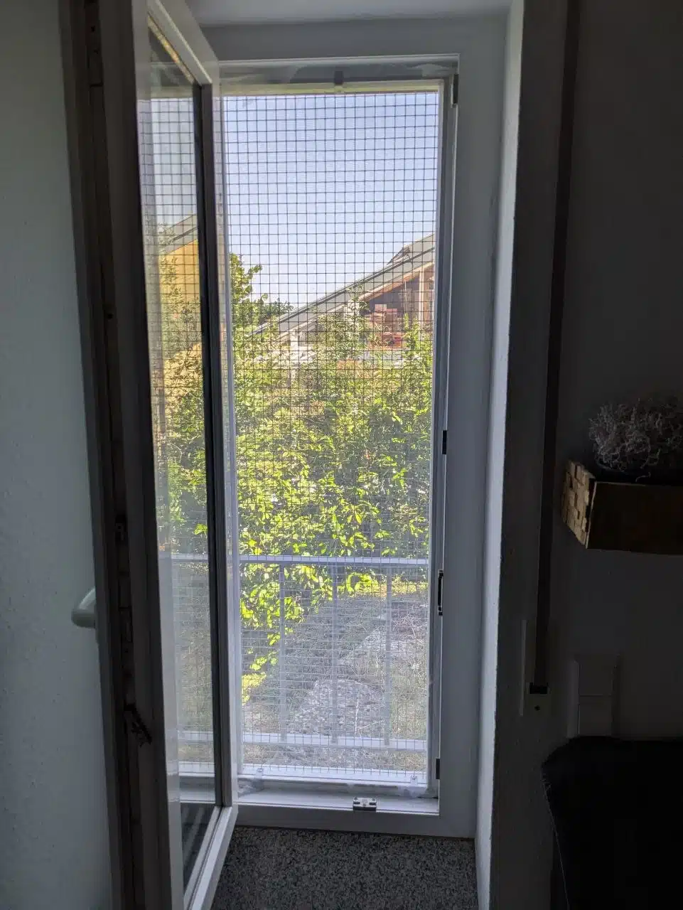 Fenster komplett geöffnet mit montiertem Katzengitter und zusätzlichem Fliegennetz, Blick nach draußen ins Grüne