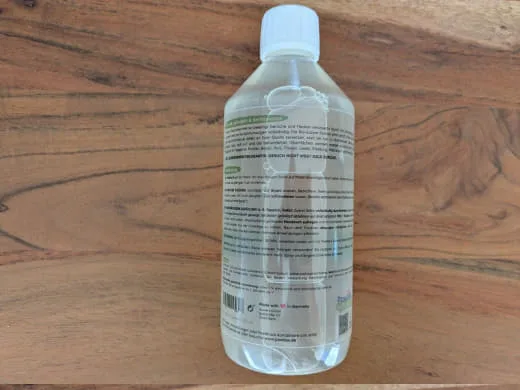 Rückseite der verschlossenen Pawlie's Geruchsentferner-Flasche auf einem Holztisch