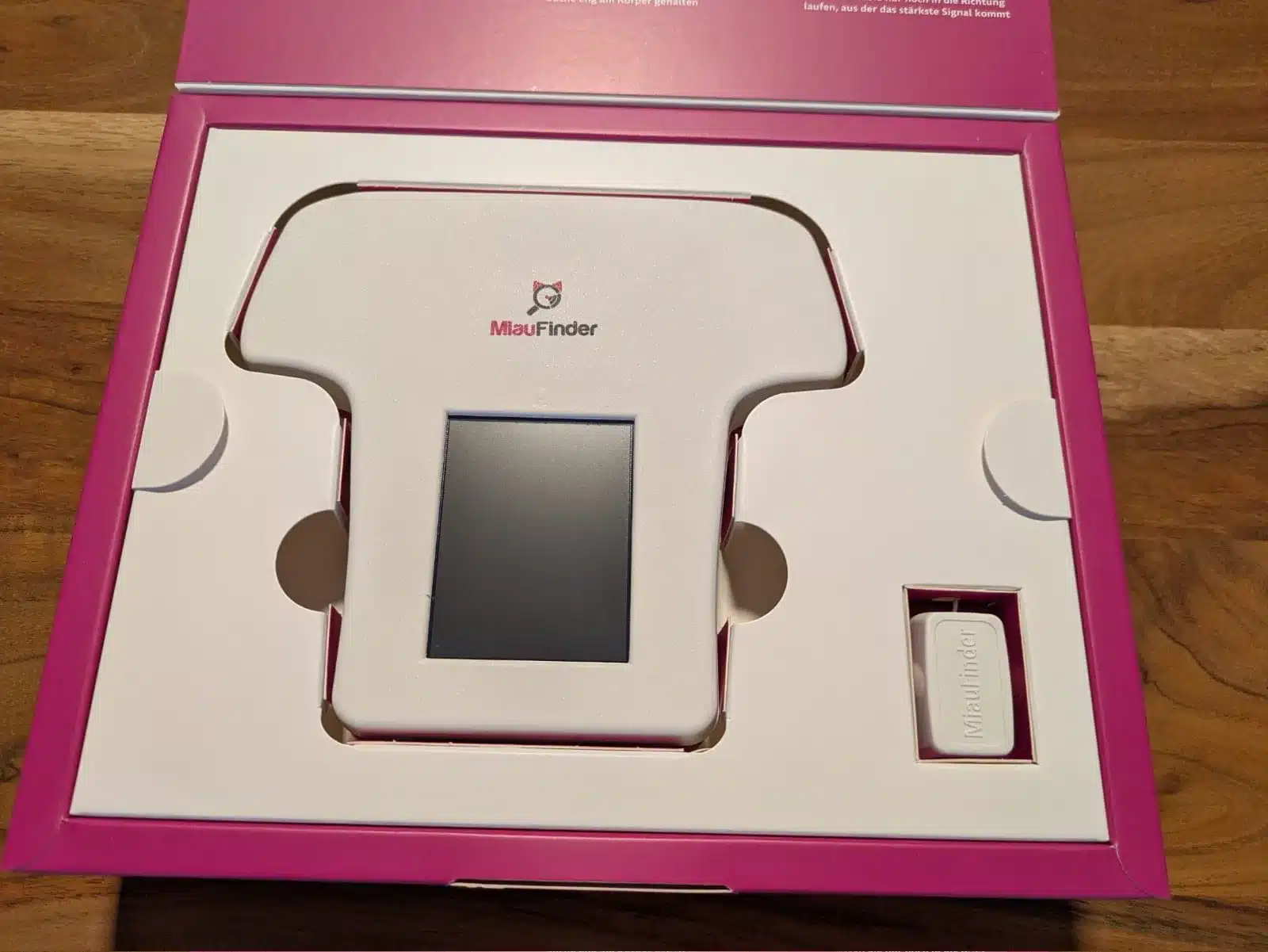 Weißer MiauFinder-Handempfänger mit ausgeschaltetem Display neben dem kleinen Halsbandsender